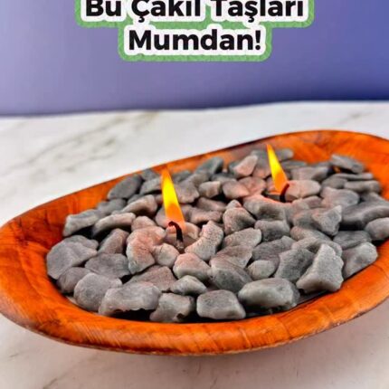 Çakıl taşı görünümlü mumlar ahşap bir kap içinde. "Bu Çakıl Taşları Mumdan!" yazısı.