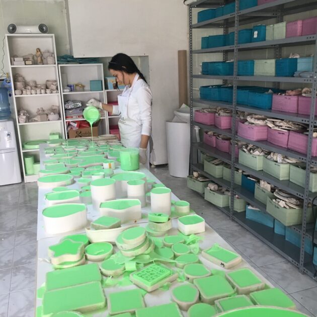 Yeşil sıvı ile silikon kalıplara döküm yapan kadın. Silikon kalıp seçimi için ideal görsel.