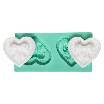 İkili fiyonklu kalp figürü silikon kalıbı ve dökülmüş beyaz objeler. Aşk temalı hediyeler için ideal.